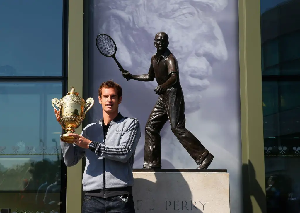 Andy Murray of Great Britain poses with Wimbledon singles trophy next to the Fred Perry statue at Wimbledon in 2013.
