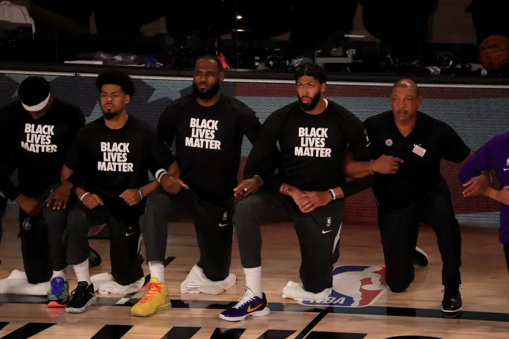  LeBron James #23 and Anthony Davis #3 of the Los Angeles Lakers in a Black Lives Matter Shirt kneel with their teammates.