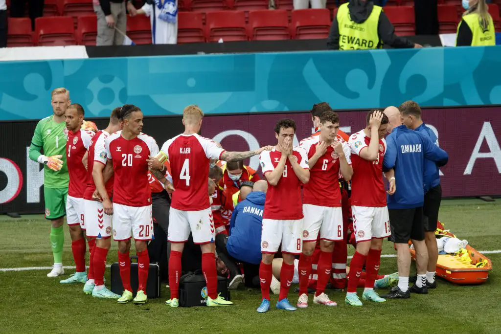 Denmark players form a wall to protect Christian Eriksen's privacy during emergency treatment. The game resumed after a long interval and Finland won. 